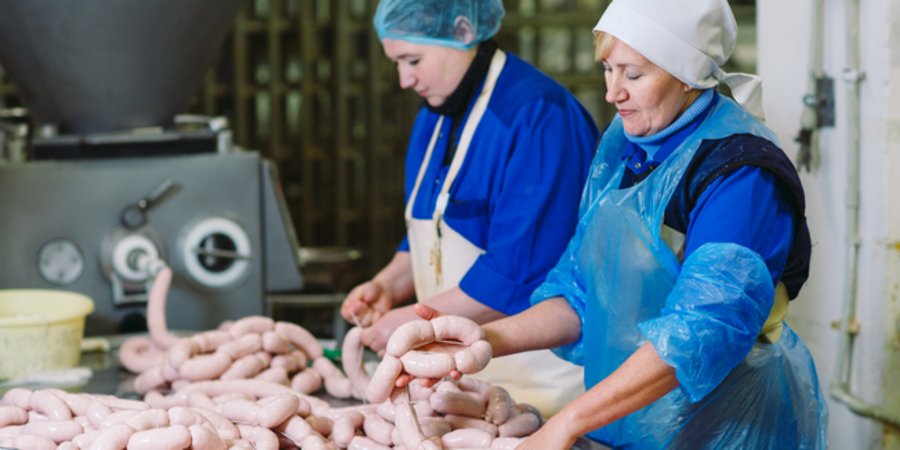 Butchers processing sausages at a meat factory.